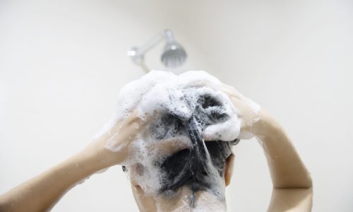 Lady using shampoo wash / clean her hair in a bathroom with splash shower spray water